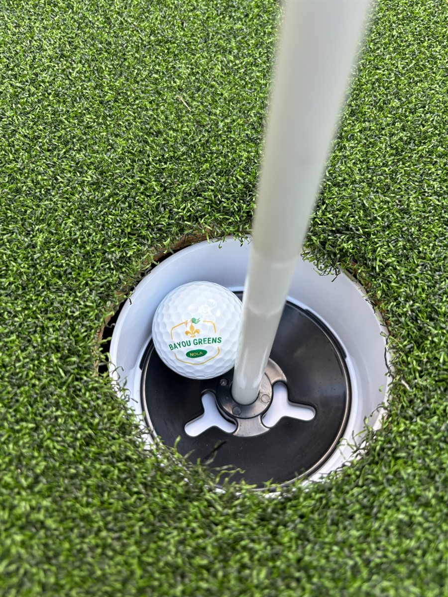 Bayou Greens NOLA branded golf ball in the cup